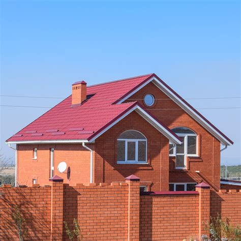 painted brick house with metal roof|matching brick and roof colors.